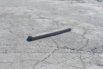 Wooden board lies at the bottom of dry alkaline lake white natural background with cracked texture