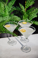 Classic Margarita cocktail with salted border on a wooden table with lemon and utensils greens background