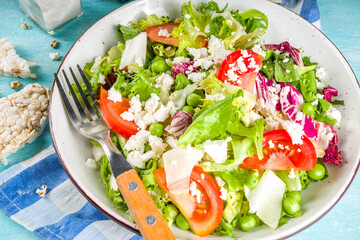 Vegan and vegetarian summer food background. Vegetable salad, with tomato, lettuce, cheese, fresh green lunch. Healthy eating concept. Light blue background copy space