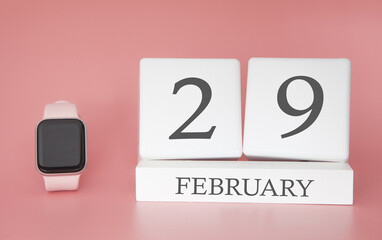 Modern Watch with cube calendar and date 29 february on pink background. Concept winter time vacation.