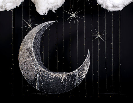 Photo booth zone studio with silver moon for sat and black wall with stars.