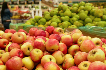 A pile of red apples lies in a drawer in a supermarket. A close-up red apples counter in a store waiting for buyers.