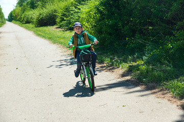 Fototapeta premium Boy on bicycle at summer asphalt road. Kid cycling outdoors. Summer sport activity concept. Soft focus