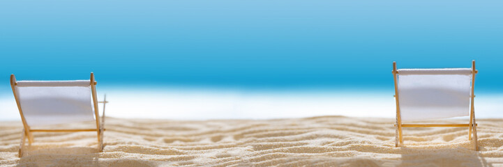 Banner 3:1. Deck chairs on sandy beach with blurry blue ocean and sky. Social distancing or...