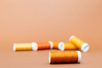 Close up of spools of thread in brown/golden colors on a brown background. Room for copy. 