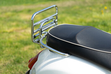 black leather seat of an italian motor scooter, back light and luggage rack, close up