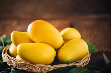 Mango tropical fruit with green leaf in wooden basket put on wooden background with copy space