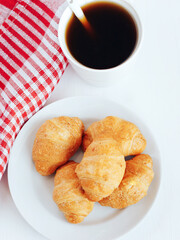Mini croissants and cup of coffee on white background.