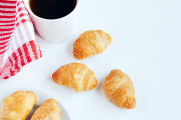 Mini croissants and cup of coffee on white background.