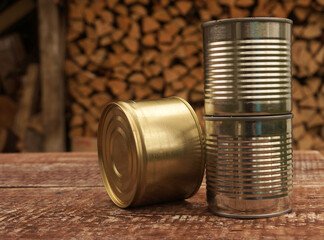 Three iron cans stand on a wooden table outdoors  