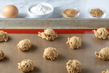 Dough balls on a baking sheet beside cooking ingredients