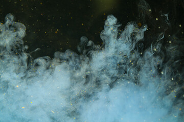 paint ink light blue in water, clouds of paint in water on a black background