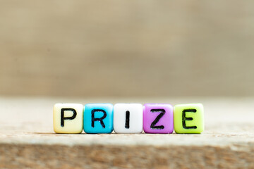 Colorful bead with black letter in word prize on wood background