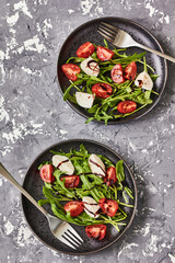 Caprese salad. Healthy meal with cherry tomatoes, mozzarella balls, spices, fresh arugula . Home made, tasty food.  Concept for a tasty and healthy vegetarian meal. Top view
