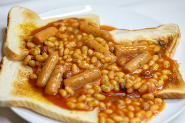 Closeup food photography - beans on toast and sausages with out of focus elements