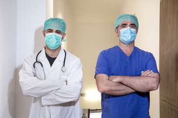 Fototapeta na wymiar Coppia di medici con cuffia e mascherina protettiva cono fermi in piedi nella corsia di un ospedale