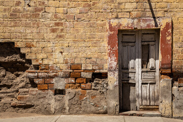 old wooden door in a stone wall - old and ruined facade from an old house