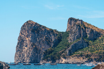 Fototapeta premium View from the public beach to the mountains. The small town of Nerano. Cove with ships and boats. Summer day. Vacation and vacation concept in Italy. Naples coast