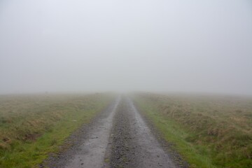 A dirt road to the fog on the field