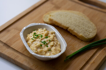 German Bavarian beer garden cheese spread made with Camembert, butter, beer, paprika and scallions on a wooden background with homemade sourdough bread slices and scallions
