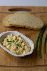 German Bavarian beer garden cheese spread made with Camembert, butter, beer, paprika and scallions on a wooden background with homemade sourdough bread slices and scallions