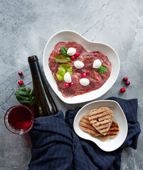 Marble beef carpaccio with mozzarella and red wine on a marble table. The view from the top.