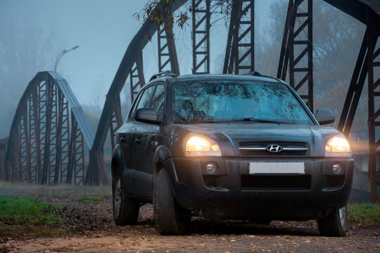 Perechin, Ukraine - OCT 20, 2019: suv headlights in foggy darkness. car on the old metal bridge with turned on light in mist environment