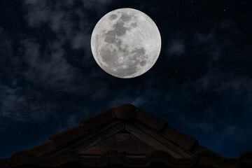 Full moon over roof in the night.