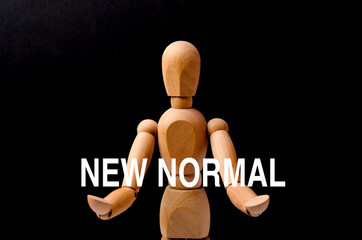 Wooden figure with text "NEW NORMAL" on black background.