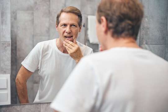 Man examining his face in the mirror