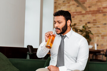 unemployed african american man drinking beer at home