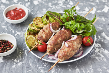 Grilled Lula kebab lamb with onions, salad, tomato and zucchini  on plate. Asian traditional meat dish