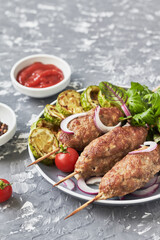 Grilled Lula kebab lamb with onions, salad, tomato and zucchini on plate. Asian traditional meat dish	