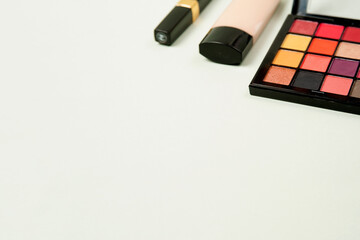 a palette of bright shadows, Foundation and mascara isolated on a light grey background with space...