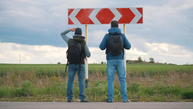 Teamwork. People are tourists, businessmen with backpacks approach the road sign of the direction of the road and choose the path. The problem of choice, decision making. Business travel concept.