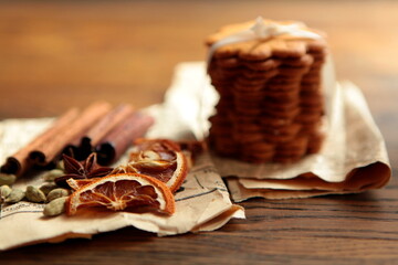 Homemade tasty gingerbread cookies on dark rustic wooden table, copy space. Healthy vegan organic nutrition concept. whole grain cookies with dried oranges, cinnamon stick, old paper, spices and herbs