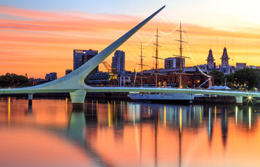 Bridge and frigate on the pier, at twilight, with city buildings and cranes around, and reflections...