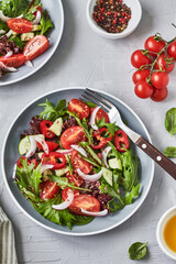 Healthy vegetable salad of fresh tomato, cucumber, pepper, onion, lettuce, arugula, flax seeds and olive oil on plate. Diet menu	