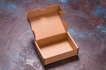 Single brown cardboard box opened, with cover on dark background
