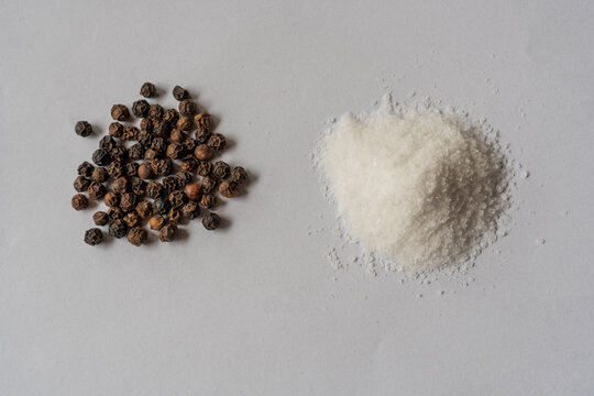 Dried Whole Seed Of Black Pepper And White Coarse Sea Salt Isolated On A White Background Seen From Above