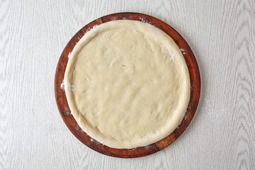 Pizza dough, 2nd step of spreading the pizza dough on wooden board isolated on gray background....