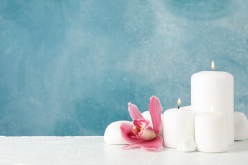 Beautiful orchid, candles and spa stones on white table, space for text