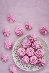 Fototapeta na wymiar Pink meringues on plate, colorful background, top view