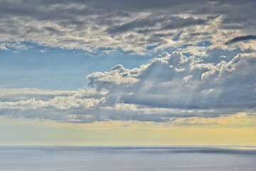 Fototapeta na wymiar Sun shines through rain clouds over Tasman sea horizon