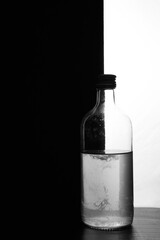 A small bottle on a black and white background. Half black and half white