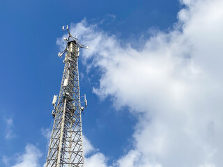 Obraz premium Cellular Base Station or Base Transceiver Station. Telecommunication tower. Wireless Communication Antenna Transmitter. 3G, 4G and 5G Cell Site with blue and cloudy sky.