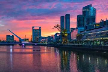 Raamstickers Puerto Madero Bridge and city by the river, during sunrise, with colorful clouds.  © Bernardo Galmarini