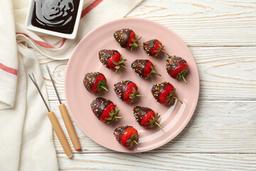 Chocolate fondue. Strawberry in chocolate on white wooden background