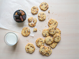 Fresh juicy date cookies with milk on a light wooden surface