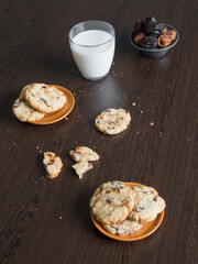 Fresh juicy date cookies with milk on a dark wooden surface